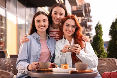 Photo of Happy friends drinking coffee in outdoor cafe