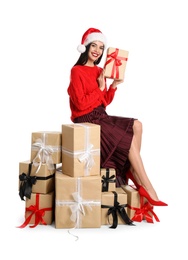 Woman in red sweater and Santa hat with Christmas gifts on white background