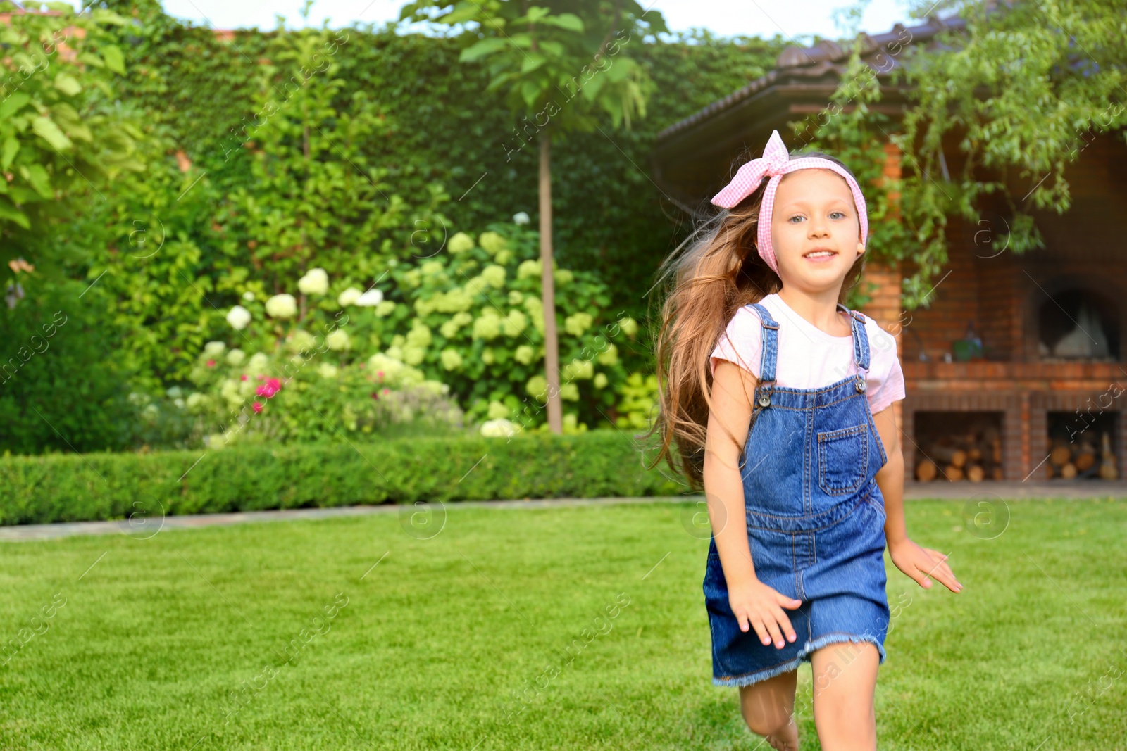 Photo of Cute little girl running in green park on summer day