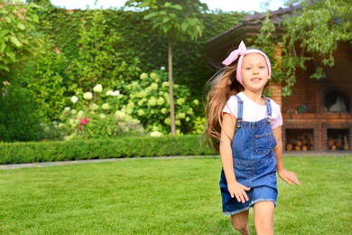 Photo of Cute little girl running in green park on summer day