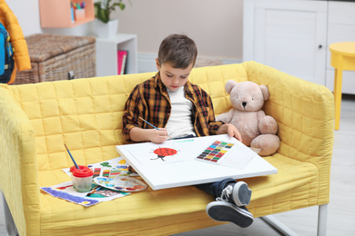 Photo of Little child painting on sofa at home