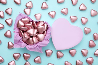 Box and delicious heart shaped candies on light blue background, flat lay