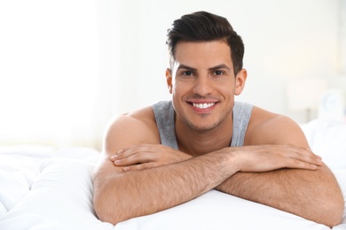 Photo of Portrait of happy handsome man lying on large bed