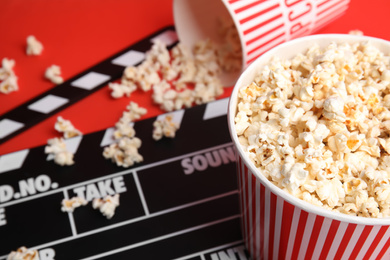 Photo of Tasty pop corn and clapboard on red background