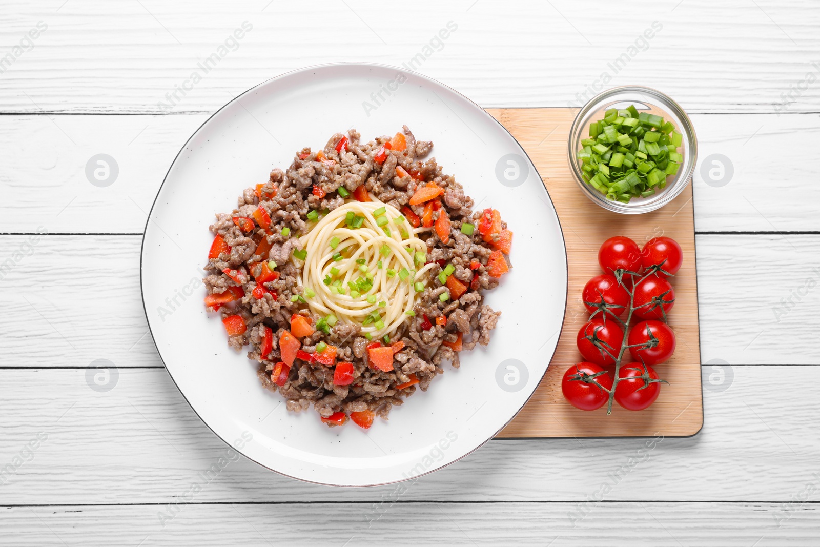 Photo of Tasty minced meat with spaghetti, vegetables and green onion on white wooden table, top view