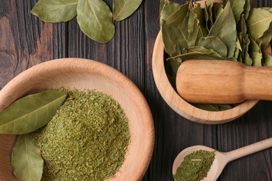 Photo of Mortar, pestle with whole and ground aromatic bay leaves on wooden table, flat lay