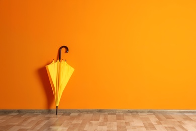 Photo of Beautiful umbrella on floor near color wall with space for design