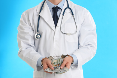 Photo of Doctor in handcuffs with bribe on light blue background, closeup. Corrupted medicine