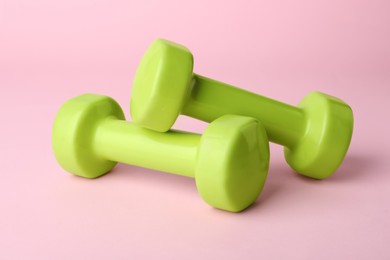 Photo of Two green dumbbells on light pink background