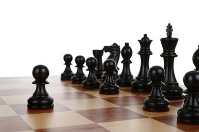 Black pawn in front of other chess pieces on wooden board against white background