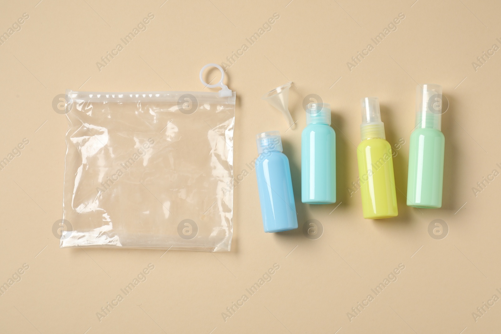 Photo of Cosmetic travel kit and plastic bag on beige background, flat lay. Bath accessories