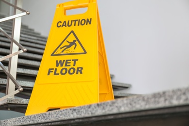 Safety sign with phrase Caution wet floor on stairs. Cleaning service