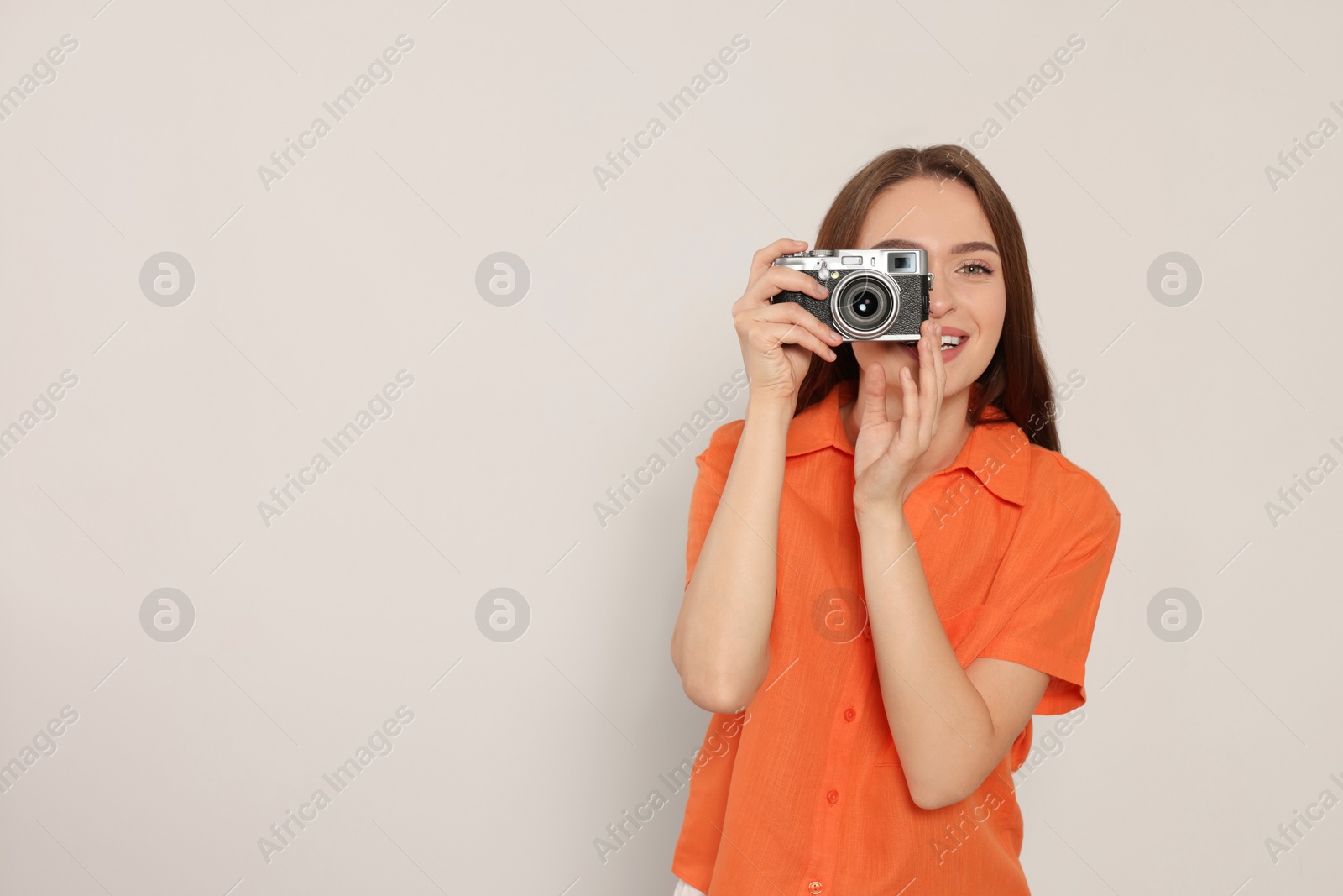 Photo of Young woman with camera taking photo on white background, space for text. Interesting hobby