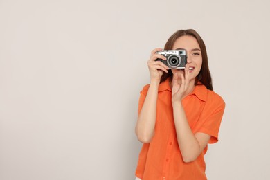 Young woman with camera taking photo on white background, space for text. Interesting hobby