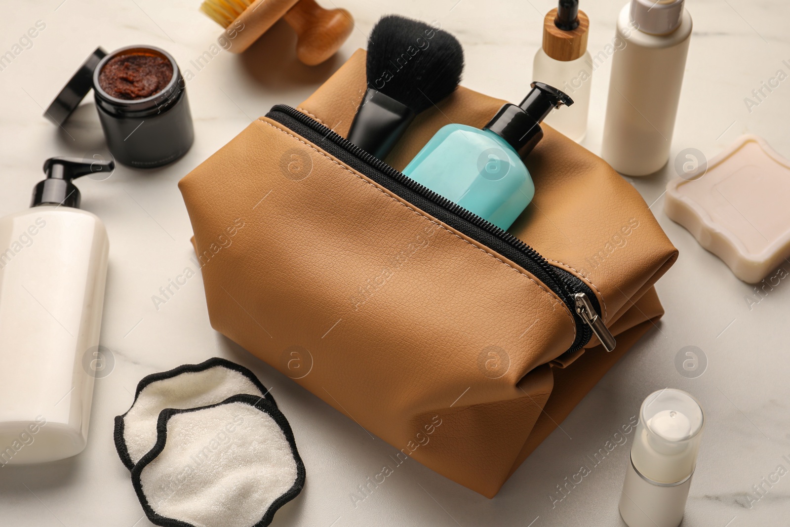 Photo of Preparation for spa. Compact toiletry bag and different cosmetic products on white marble table