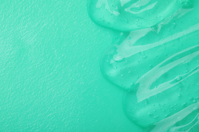 Photo of Sample of transparent cosmetic gel on turquoise background, top view