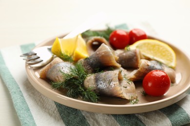 Salted herring fillets served with cherry tomatoes, dill and lemon on light beige table, closeup