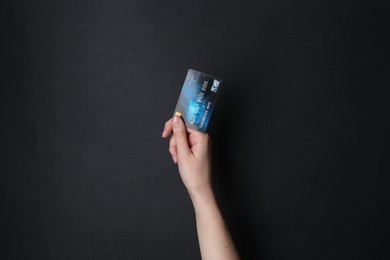 Woman holding credit card on black background, closeup