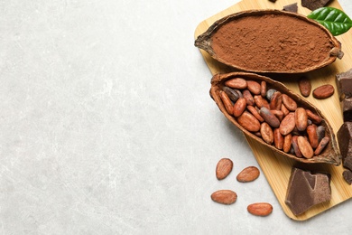 Photo of Flat lay composition with cocoa pods, powder and beans on light table. Space for text