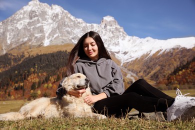 Beautiful young woman with adorable dog in mountains on sunny day