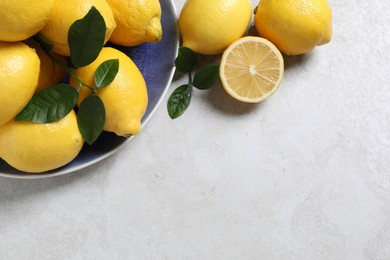 Photo of Fresh lemons and green leaves on table, flat lay. Space for text