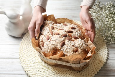 Photo of Woman with delicious Italian Easter dove cake (traditional Colomba di Pasqua) at white wooden table, closeup