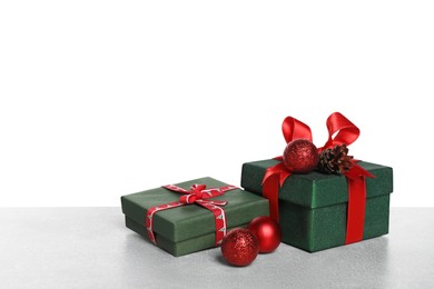 Photo of Christmas gifts in beautiful decorated boxes on grey table against white background, space for text