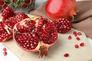 Piece of fresh pomegranate and seeds on white table, closeup