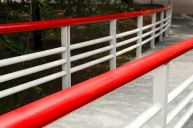 Photo of Ramp with red metal handrailings near trees outdoors