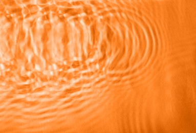 Image of Concentric waves on water surface after falling drops, top view. Toned in orange