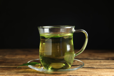 Photo of Cup of aromatic green tea on wooden table