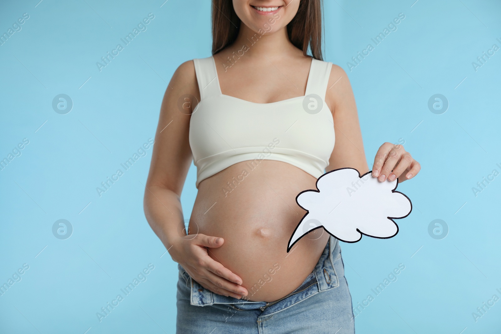 Photo of Pregnant woman with empty paper thought cloud on light blue background, closeup. Choosing baby name