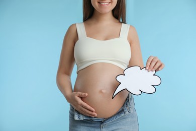 Pregnant woman with empty paper thought cloud on light blue background, closeup. Choosing baby name