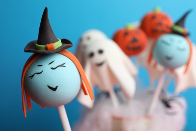 Delicious Halloween themed cake pops on light blue background, closeup. Space for text