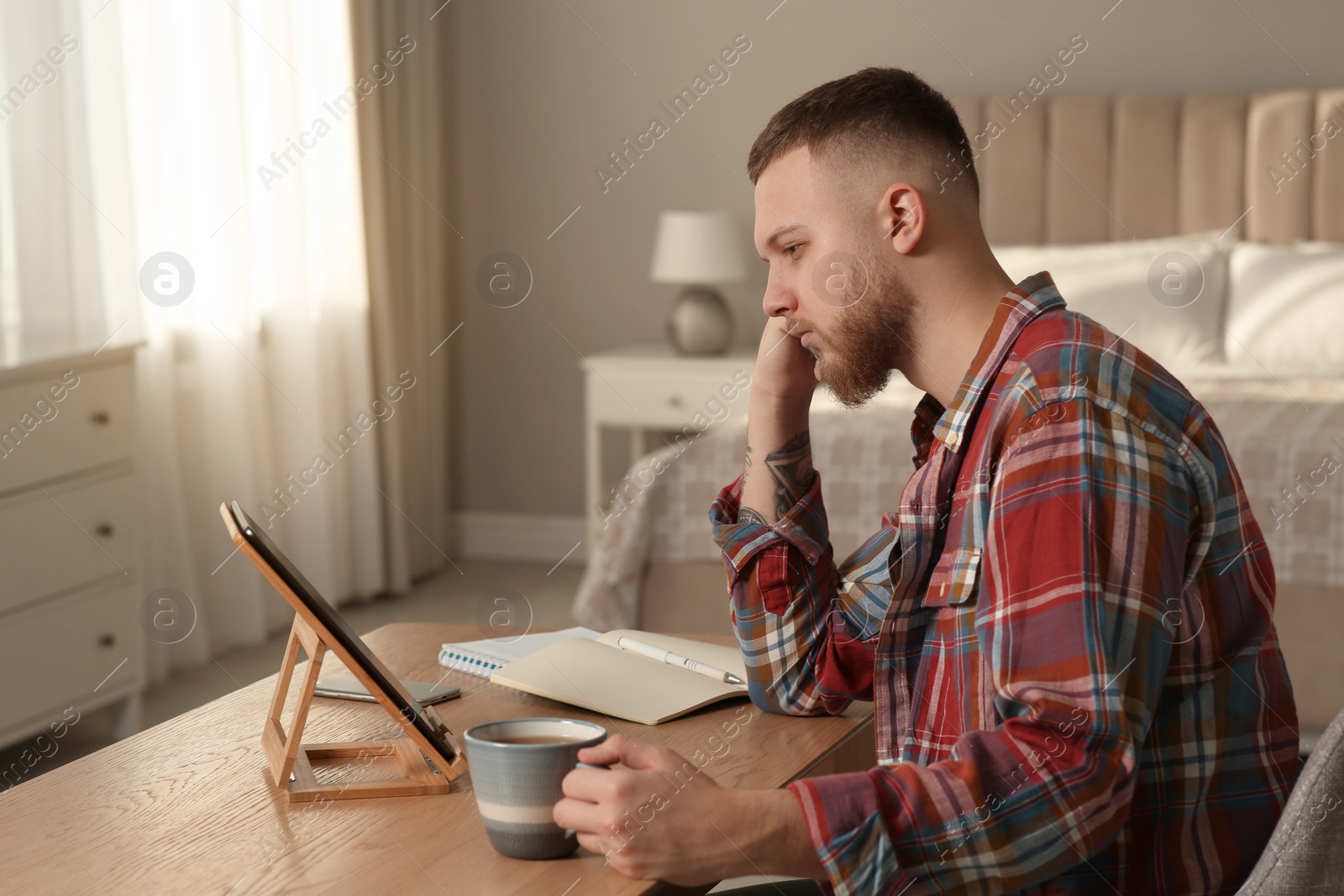 Photo of Online test. Man studying with tablet at home