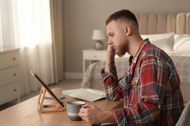 Photo of Online test. Man studying with tablet at home