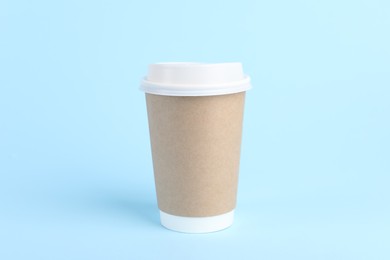 Photo of Paper cup with plastic lid on light blue background. Coffee to go