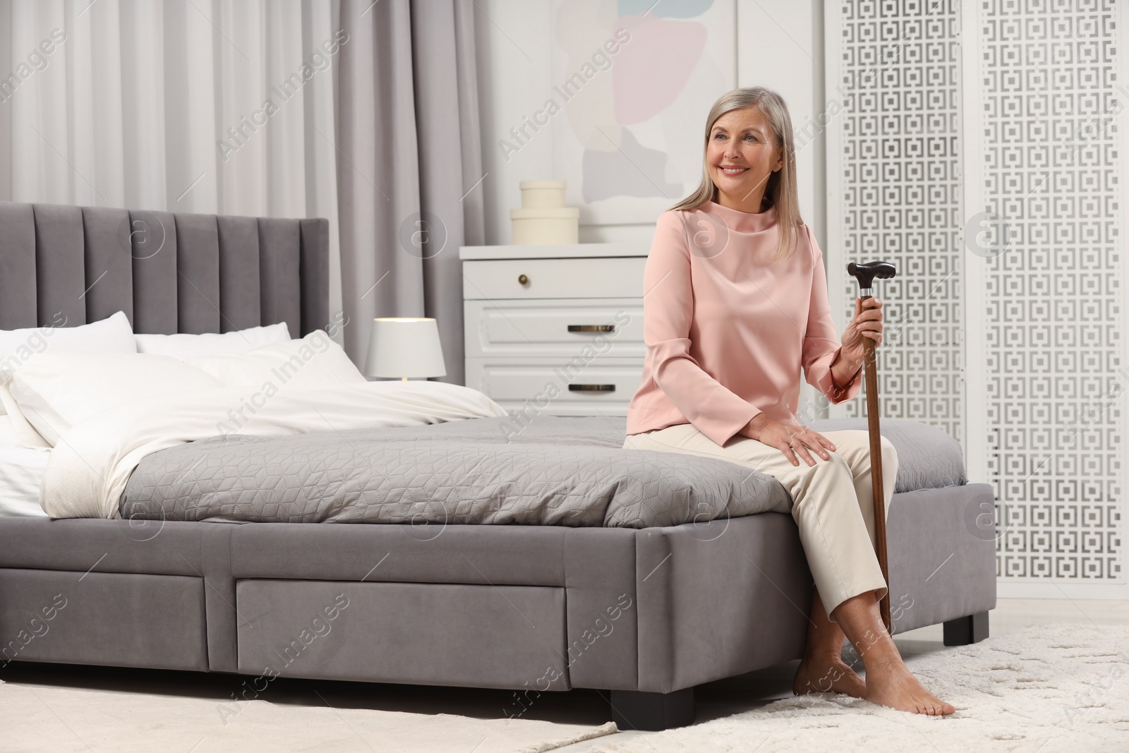 Photo of Mature woman with walking cane on bed at home