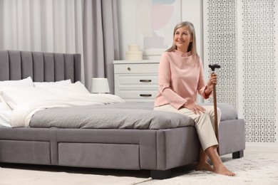 Mature woman with walking cane on bed at home
