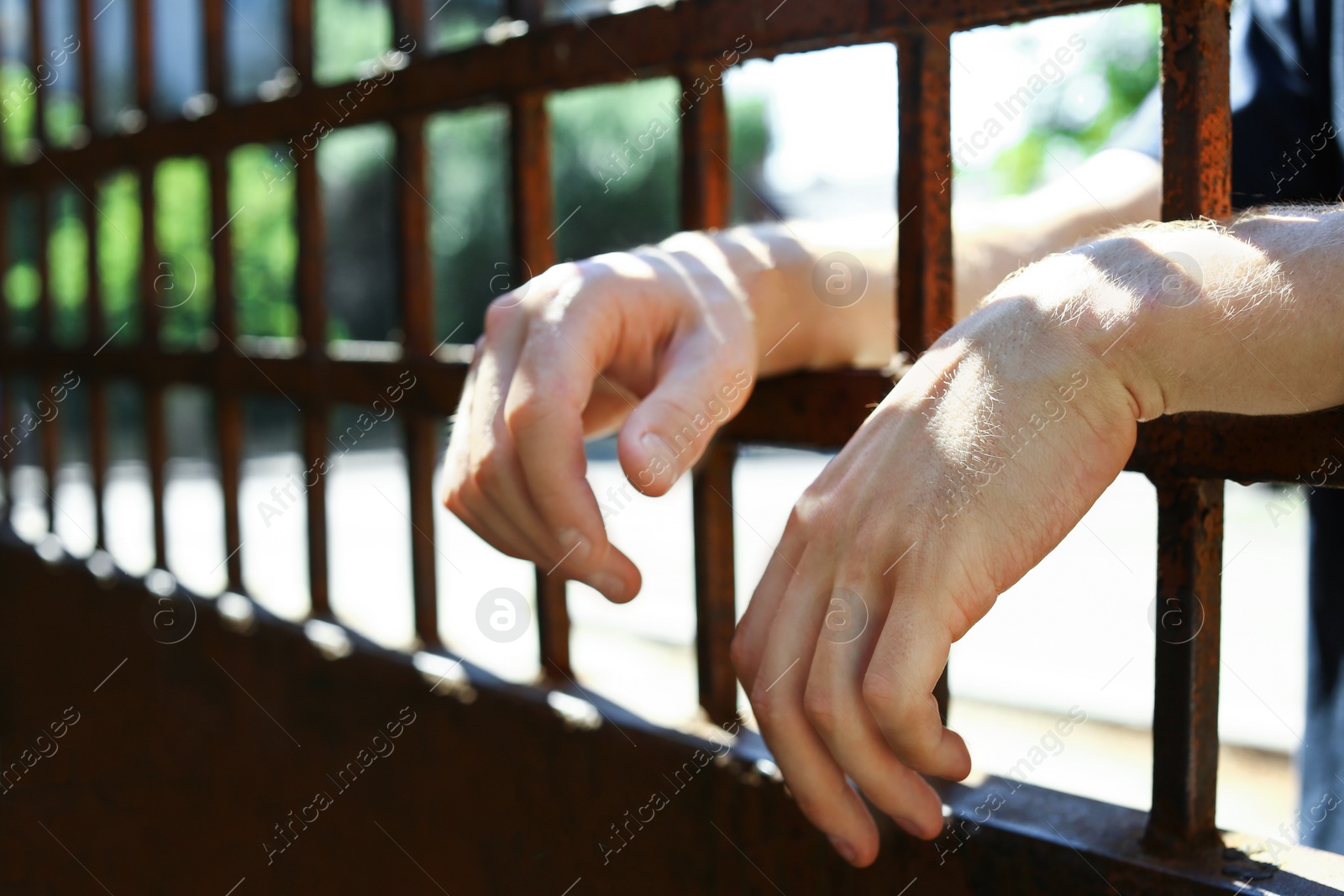 Photo of Man detained in jail outdoors, closeup. Criminal law