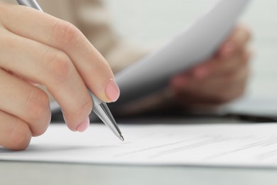 Photo of Woman signing document at table, closeup view. Space for text