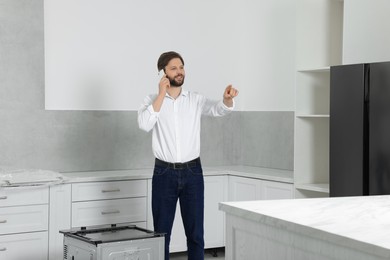 Photo of Man talking on smartphone in empty kitchen