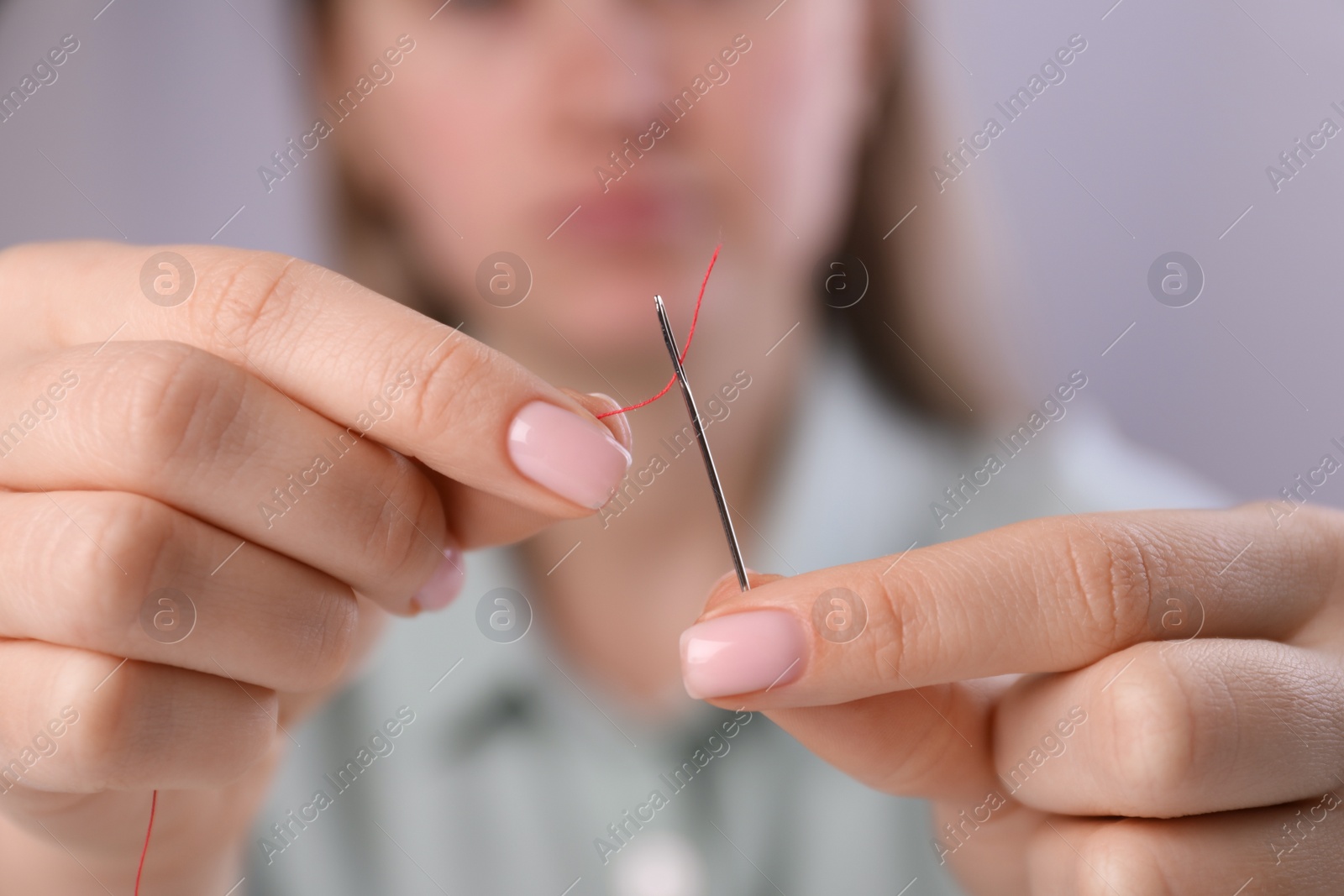 Photo of Woman threading needle, closeup view. Sewing equipment