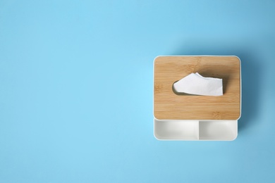 Photo of Holder with paper tissues on light blue background, top view. Space for text