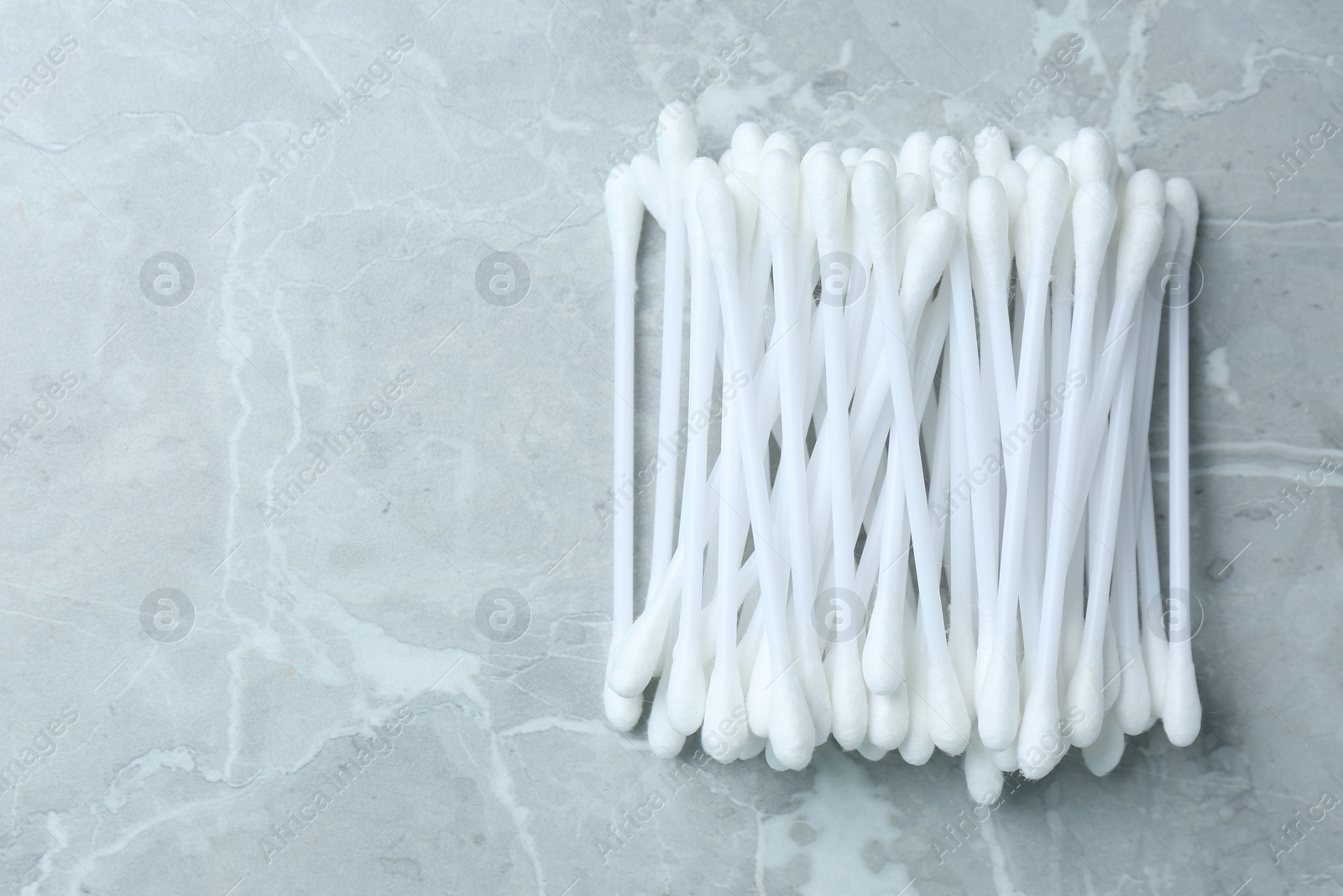 Photo of Many cotton buds on light grey marble table, flat lay. Space for text