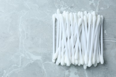 Many cotton buds on light grey marble table, flat lay. Space for text