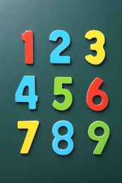 Colorful numbers on green background, flat lay