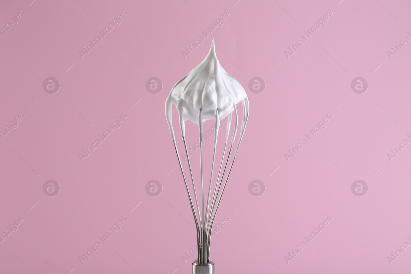 Photo of Whisk with whipped cream on pink background