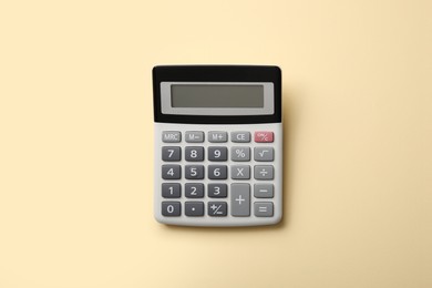 Calculator on beige background, top view. Space for text