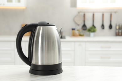 Photo of Modern electric kettle on table in kitchen. Space for text